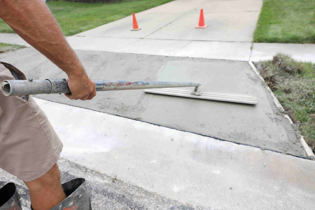 This photo shows a concrete contractor finishing up the installation process of a concrete pathway.