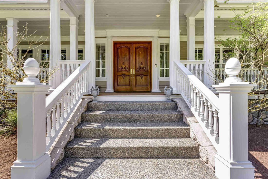 This photo shows a luxury home that has an exposed aggregate stair set. The pathway leading to the stairs also uses exposed aggregate concrete for a smooth transition. 